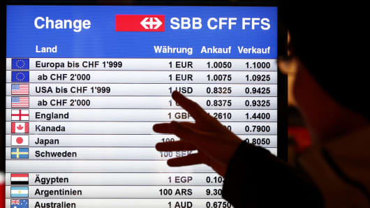 A man looks at a board showing currency exchange rates in Bern January 15, 2015.