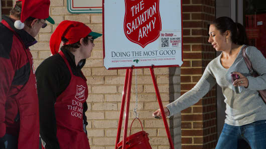 A woman(R) makes a donation into a Salvation Army kettle outside a Giant grocery store in Clifton, Virgina.