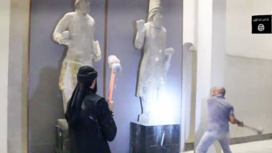In this image made from video posted on a social media account affiliated with the Islamic State group on Thursday, Feb. 26, 2015, which has been verified and is consistent with other AP reporting, militants attack ancient artifacts with sledgehammers in the Ninevah Museum in Mosul, Iraq.