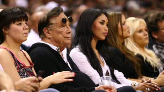 Former team owner Donald Sterling of the Los Angeles Clippers and V. Stiviano watch the San Antonio Spurs play