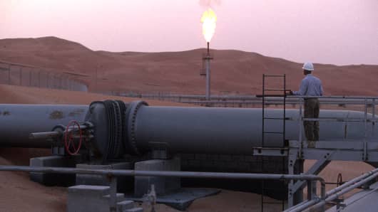 A worker stands at a pipeline, watching a flare stack at the Saudi Aramco oil field complex facilities at Shaybah in the Rub' al Khali ('empty quarter') desert in Shaybah, Saudi Arabia.
