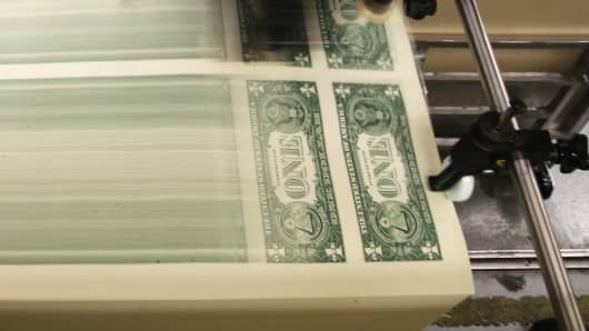 Sheets of one dollar bills run through the printing press at the Bureau of Engraving and Printing in Washington, DC.