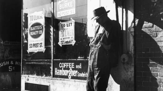 Unemployed man stands against a vacant store on "Skid Row,"  Howard Street, San Francisco, February 1937, in this photograph by Dorothea Lange.