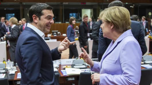 Greek Prime Minister Alexis Tsipras talks with German Chancellor Angela Merkel at a European Union leaders summit in Brussels.