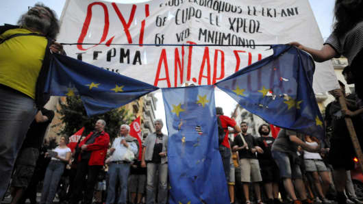 Anti-EU protesters hold a burned and torn European Union flag during a protest at the northern city of Thessaloniki, Greece July 1, 2015. A defiant Prime Minister Alexis Tsipras urged Greeks on Wednesday to reject an international bailout deal, wrecking any prospect of repairing broken relations with EU partners before a referendum on Sunday that may decide Greece's future in Europe.