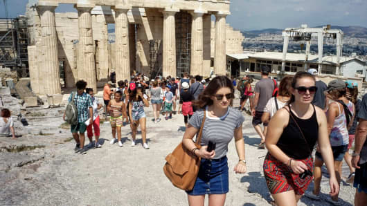Tourists visit the ancient Acropolis hill, with the ruins of the Parthenon temple in Athens.
