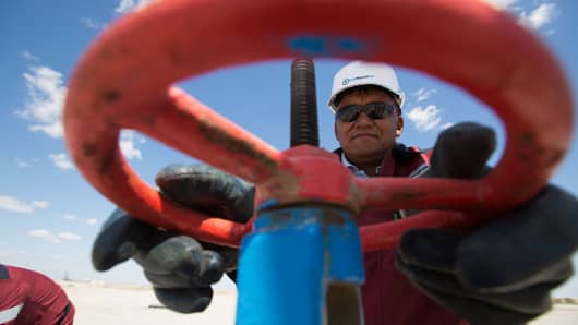 An oil worker adjusts a flow valve at an oilfield operated by Embamunaigas, a unit of KazMunaiGas Exploration Production, near Atyrau, Kazakhstan.