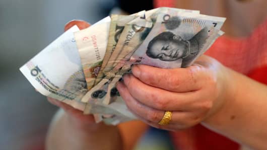 A vendor holds Chinese Yuan notes at a market in Beijing.