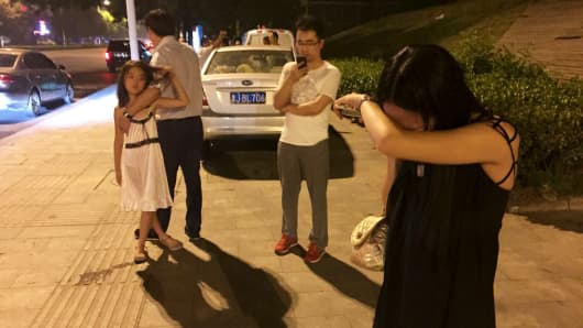 People react near a street after a blast at Binhai new district, in Tianjin municipality, China, August 12, 2015. A huge explosion hit an industrial area in the northeastern Chinese city of Tianjin late on Wednesday evening, triggering a blast wave felt several kilometres away and injuring at least 50 people, domestic media reported.
