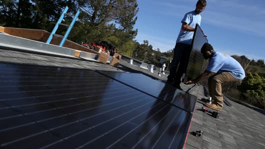 SolarCraft workers Craig Powell (left) and Edwin Neal install solar panels on the roof of a home on Feb. 26, 2015, in San Rafael, California.