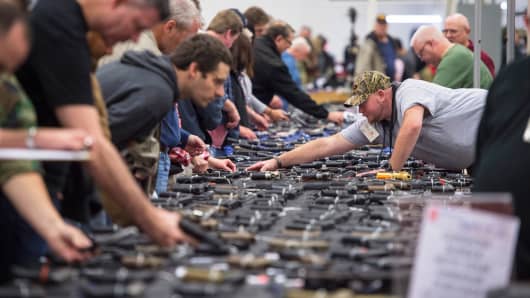 People examine handguns during The Nation's Gun Show in Chantilly, Virginia, on Oct. 3, 2015.