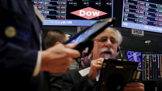 Traders work below a board displaying the Dow Chemical logo on the floor of the New York Stock Exchange in New York on Dec. 9, 2015.