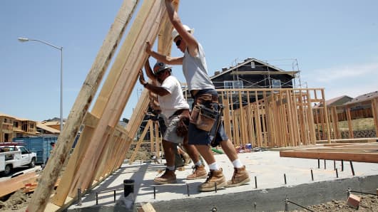 Construction workers raise wood framing as they build homes in a new housing development in Richmond, Calif.