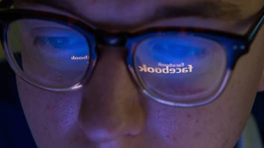 Facebook logo reflected in man's glasses