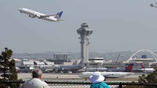 People watch as a United Airlines jet passes the air traffic control tower at Los Angles International Airport (LAX) during take-off in Los Angeles, California.