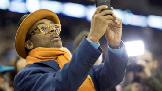Spike Lee using his mobile phone at an NBA game in London.
