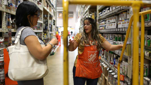 Home Depot employee helps a customer as she shops in the paint department at the store in Miami
