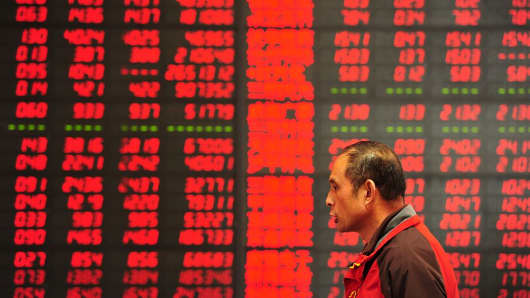 An investor makes his way in front of a screen showing stock market movements in a securities firm in Fuyang, east China's Anhui province.