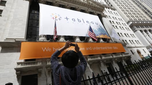 A woman takes pictures of the New York Stock Exchange, which has a Tableau Software banner, May 17, 2013.
