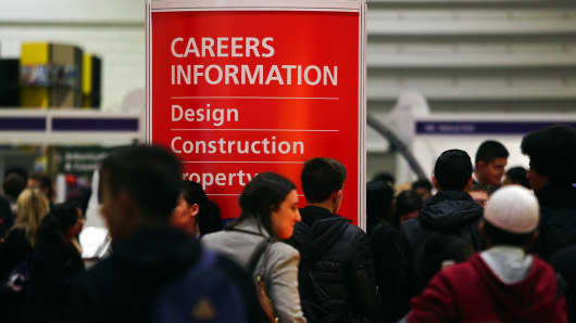 Visitors walk past a Careers Information display board as they pass job exhibition booths at a job fair