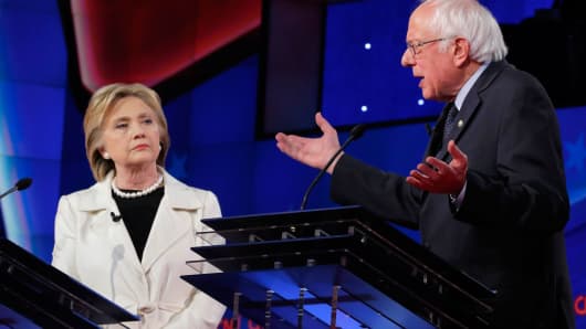 Hillary Clinton (L) listens to Senator Bernie Sanders speak during a Democratic debate at the Brooklyn Navy Yard in New York April 14, 2016.
