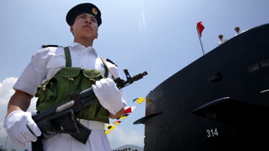 A Chinese Naval officer stands guard beside a submarine at the Ngong Shuen Chau Naval Base in Hong Kong.
