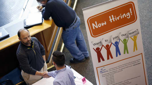 A representative, left, shakes hands with a job seeker during a Job News USA career fair.