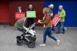A pedestrian pushes a pram past 'Vote Leave' campaigners on a high street in the Southwick district of Sunderland, U.K., on Saturday, June 4, 2016. 