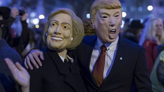 People wearing the masks of presidential candidates Hillary Clinton and Donald Trump