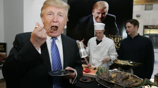 Donald Trump bites into a piece of Trump Steaks during a Sharper Image event