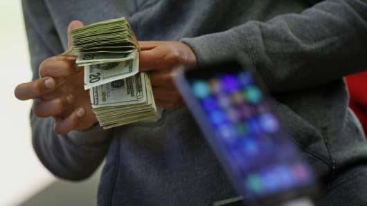 A customer counts cash to pay for two iPhone 6 smartphones during the sales launch at the Apple Inc. store in New York.