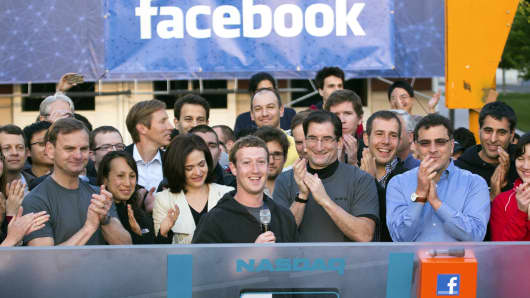 Facebook CEO Mark Zuckerberg (center) speaks remotely from Facebook's Menlo Park, California, campus for the opening of trading at Nasdaq MarketSite. COO Sheryl Sandberg (center left) and Robert Greifeld, (center right), CEO of Nasdaq OMX Group, also attended.