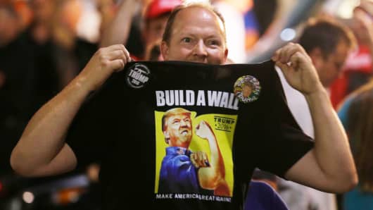 A supporter of Republican presidential candidate Donald Trump holds up his shirt, bearing the Trump slogan "Build a Wall," following a rally for Trump in Everett, Washington last August.