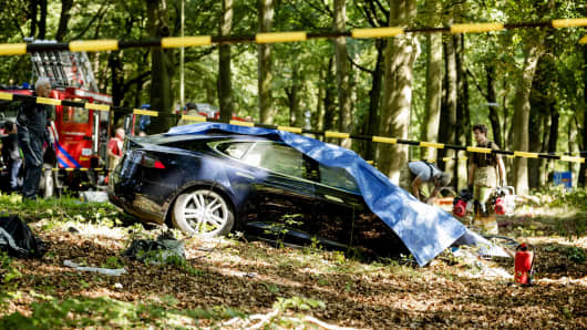 Rescue workers proceed with caution around the spot where a Tesla slammed into a tree in Baarn, Netherlands, on September 7, 2016.