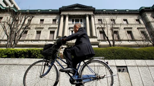 A man rides a bicycle past the Bank of Japan building in Tokyo.