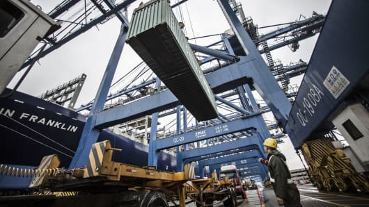 A dock worker directs the loading of shipping containers onto CMA CGM SA's Benjamin Franklin container ship docked at the Guangzhou Nansha Container Port in Guangzhou, China.