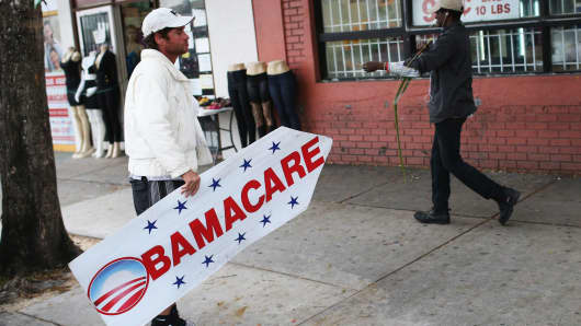 A person holds a sign directing people to an insurance company where they can sign up for the Affordable Care Act, also known as Obamacare.