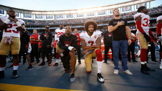 Eric Reid #35 and Colin Kaepernick #7 of the San Francisco 49ers kneel on the sideline during the anthem