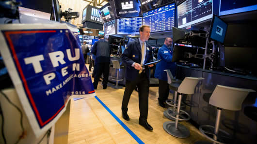 A trader walks past a campaign sign for U.S. President-elect Donald Trump and U.S. Vice President-elect Mike Pence on the floor of the New York Stock Exchange (NYSE) in New York, U.S., on Wednesday, Nov. 9, 2016.