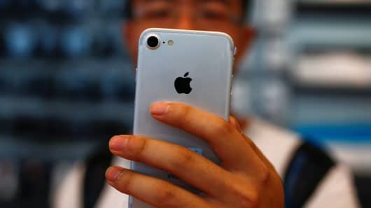 גבר מחזיק את ה- iPhone החדש שלו בחנות אפל בבייג'ינג.