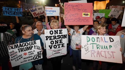 Anti-Donald Trump protesters hold signs as they gather at The Linq Promenade before marching on the Las Vegas Strip on November 12, 2016 in Las Vegas, Nevada.