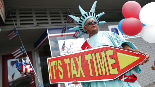 A man directs people to the Liberty Tax Service office as the deadline to file taxes looms on April 15, 2016 in Miami, Florida. 