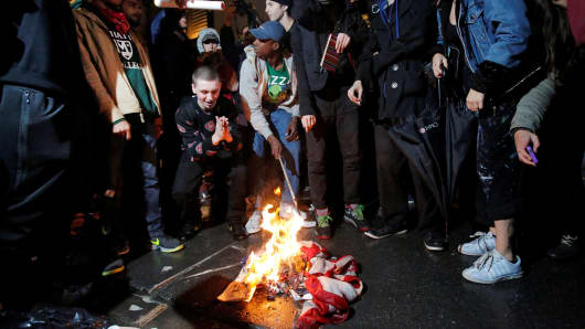 Protesters burn a U.S. flag outside Trump Tower following President-elect Donald Trump's election victory in New York, November 9, 2016.