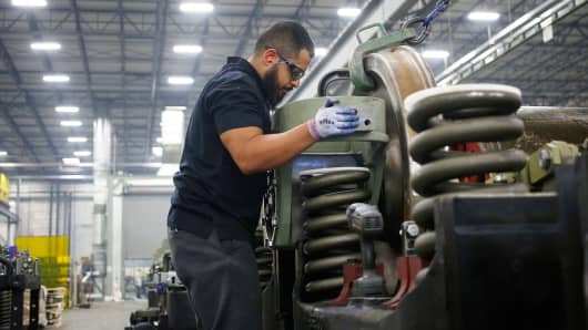 An employee helps install a traction motor onto the truck of a General Electric Evolution Series Tier 4 diesel locomotive at the GE Manufacturing Solutions facility in Fort Worth, Texas.