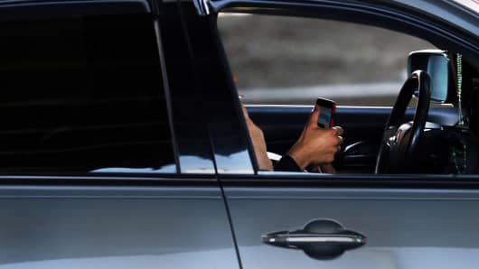 A driver uses a phone while behind the wheel of a car in New York City.