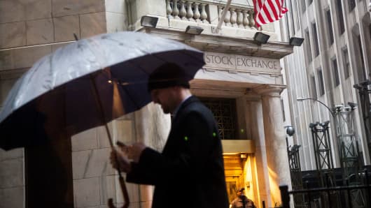 A pedestrian carries an umbrella while walking along Wall Street past the New York Stock Exchange in New York.