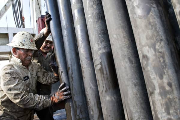 Workers guide a section of drill pipe into a rack after it was removed from a natural gas well being drilled in the Eagle Ford shale in Karnes County, Texas.