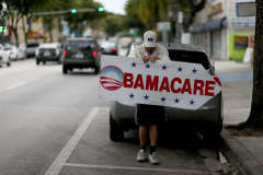 A man holds a sign directing people to an insurance company where they can sign up for the Affordable Care Act.