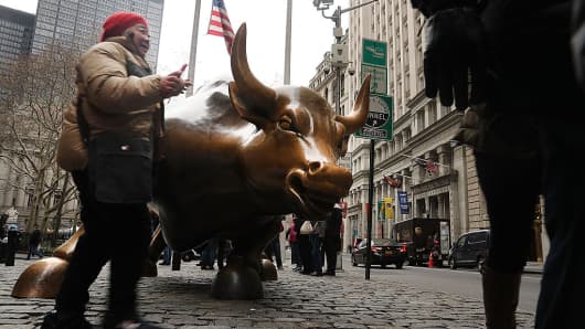 Tourists take a picture with the market bull near the New York Stock Exchange in New York City.