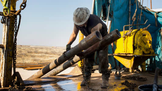 A worker prepares to lift drills by pulley to the main floor of a drilling rig in the Permian basin.